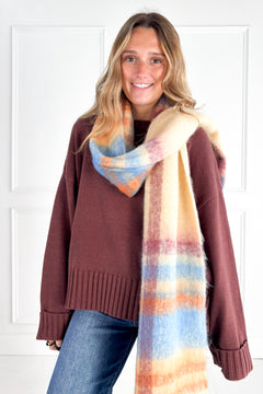 Model wearing the cocoa Cozy Cuff Oversized Sweater with jeans and a colorful striped scarf.